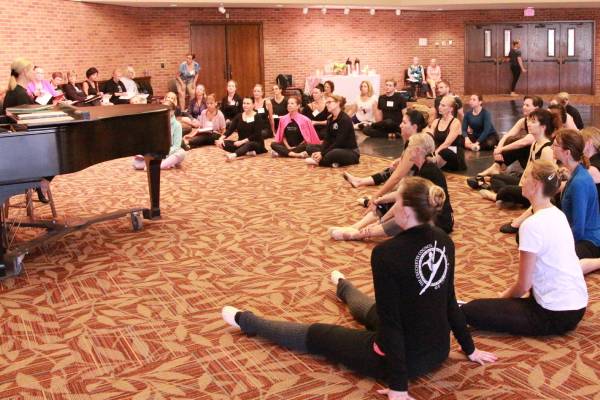 A group of people sitting on the floor listening to a woman