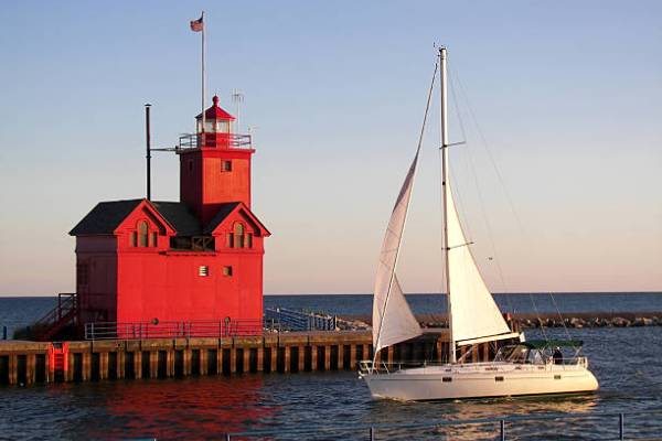 A sailboat next to a red lighthouse building