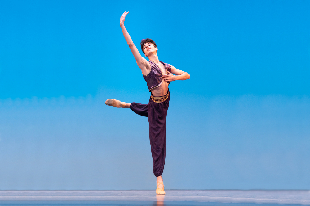 Man in a ballet position with hand in the air