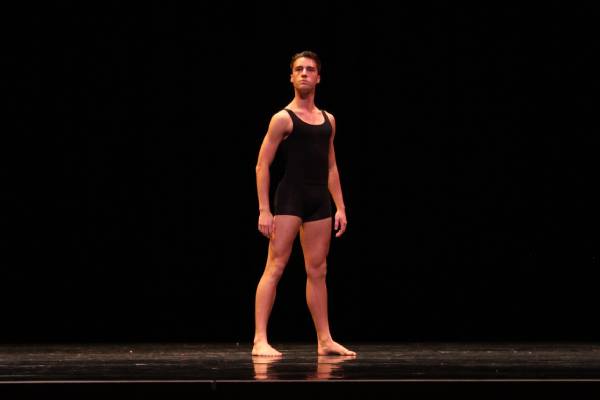 Man standing confidently on stage in a ballet outfit