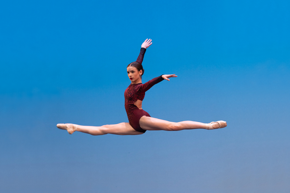 Woman in a ballet position in the air Woman jumping to reach a ballet position in the air