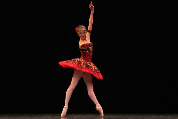 Woman in a ballet position holding a tambourine